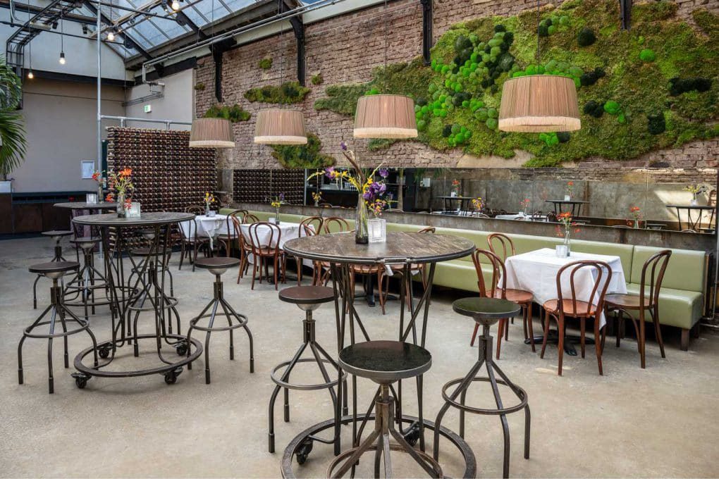 A room with tables and chairs and a moss wall.