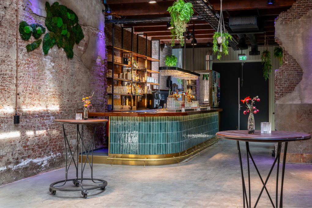 Een bar in een bakstenen gebouw met planten aan de muren.