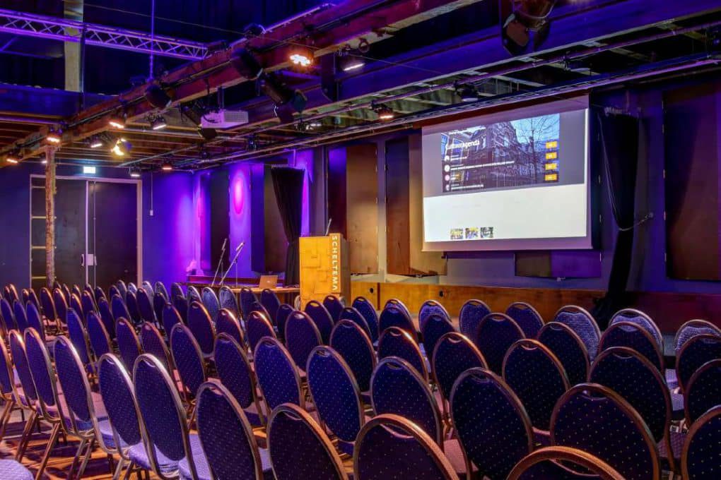 A conference room with rows of chairs and a projection screen.