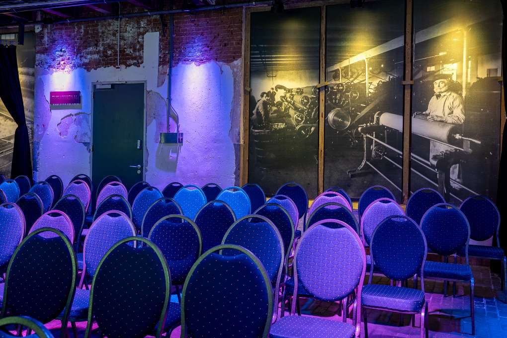 Een kamer met rijen stoelen, opgesteld voor een conferentie.